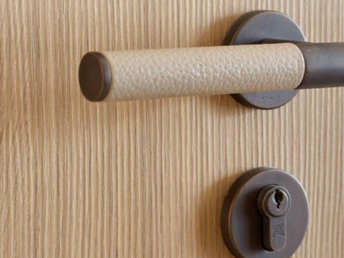Leather-wrapped lever handle and euro cylinder on an oak entrance door