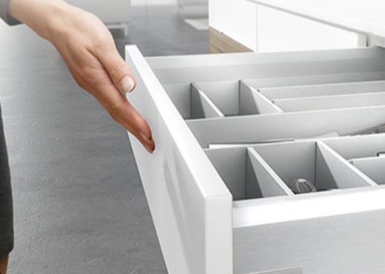 A hand opening a drawer fitted with a compartment organiser tray