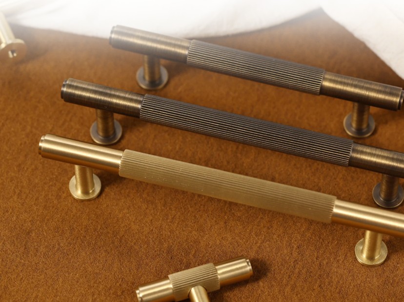 Knurled brass and bronze main door handles laid out on a leather surface